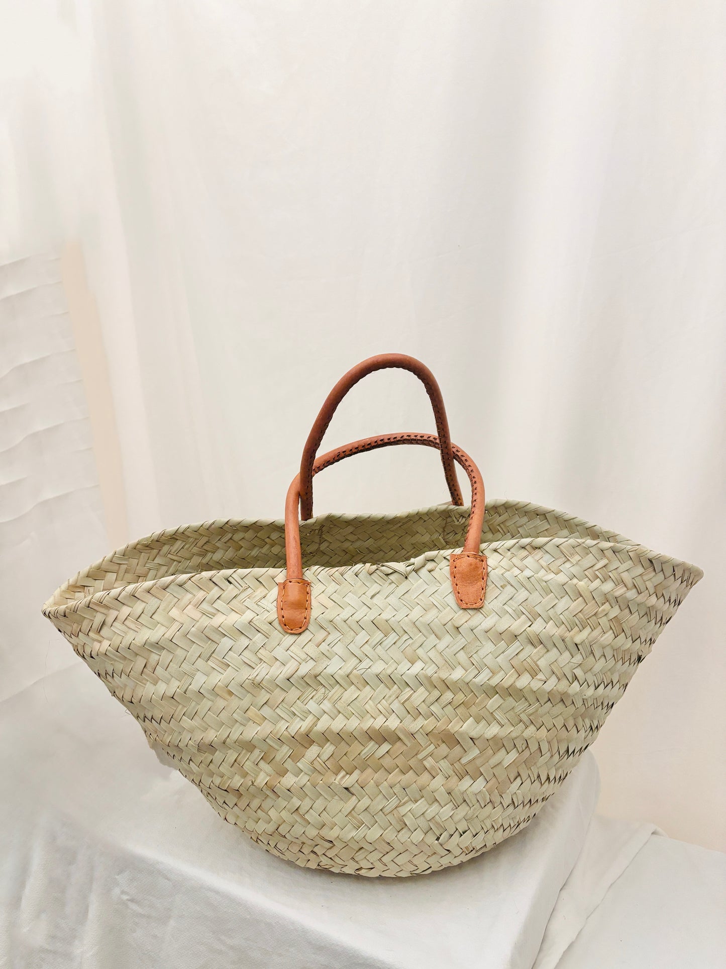 Handwoven palm leaf basket with leather handles